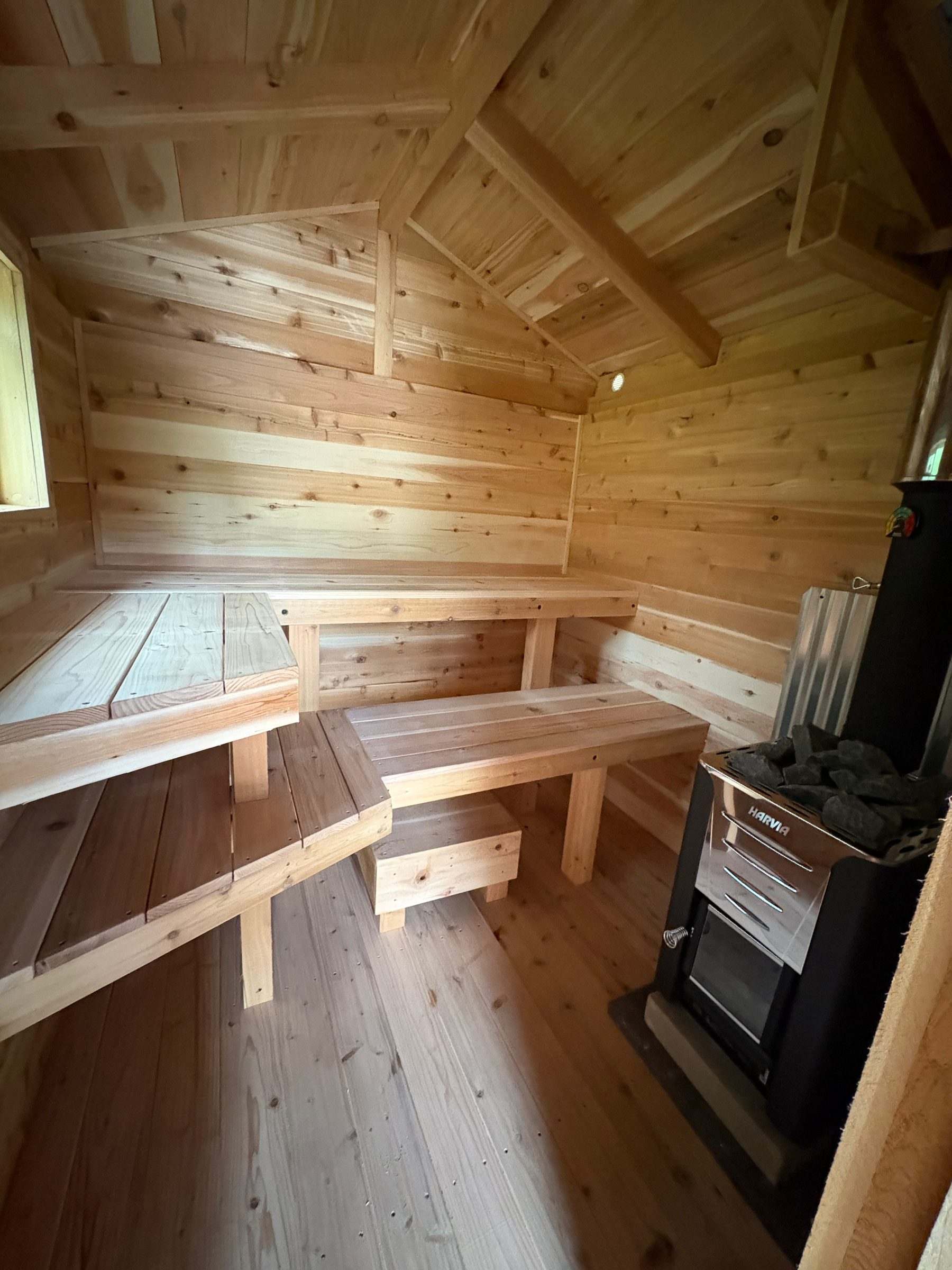 Harvia wood-burning sauna stove with sauna rocks beside tiered cedar benches